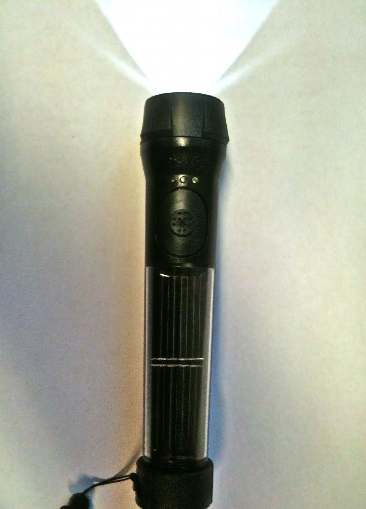 solar torch on white tabletop, illuminated, with solar cells showing